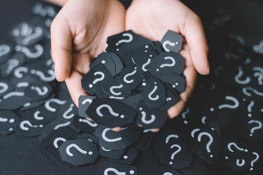 pile of white question marks on black tiles 