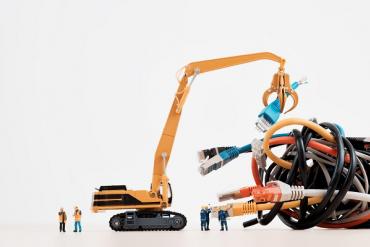 toy construction workers and construction equipment trying to put together giant, colorful ethernet cables