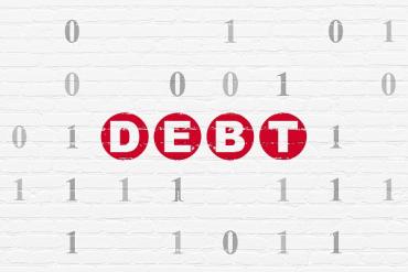 red words 'technical debt' on a white brick background covered in 1s and 0s